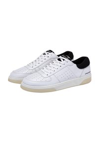 Sneaker bianche in pelle con punta perforata, dettagli neri sul tallone e sulla linguetta, lacci piatti e suola in gomma color crema.