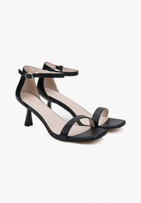 Zwarte leren sandalen met een enkelbandje, open teen en een bescheiden hak. Beschikt over een gladde textuur en een minimalistisch ontwerp.
