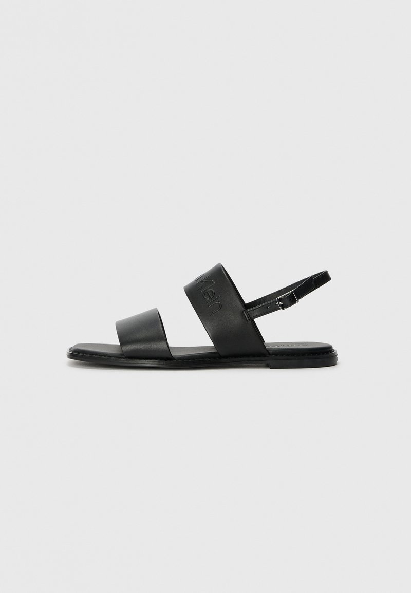 Mustad mustadest nahast sandaalid, millel on kaks laia rihma ja reguleeritav pahkluu rihm. Lame tallaga, millel on minimalistlik disain ja diskreetne brändi detail.