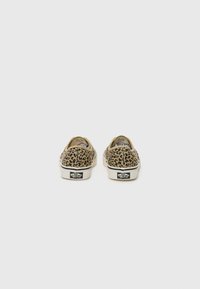 Leopard print sneakers with a canvas upper, beige base, white rubber sole, and branded heel patch, featuring a low profile design.
