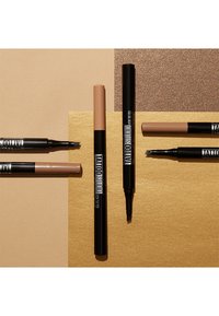 Quatre produits pour les sourcils sur un fond texturé : deux crayons à sourcils nude, un crayon noir à pointe fine et un crayon marron à grosse pointe.