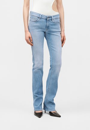 Ανοιχτό μπλε τζιν παντελόνι με ίσια γραμμή που φοριέται από άτομο με λευκό αμάνικο τοπ, μπουζωμένο μέσα στο παντελόνι, και μαύρες μυτερές γόβες.