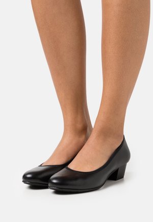 Chaussures à talons en cuir noir avec un bout arrondi, un talon bas en bloc et une large ouverture courbée à l'avant, présentant une texture lisse.