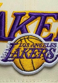 Patch de casquette des Los Angeles Lakers avec broderie violette et jaune, présentant un graphique de ballon de basketball et le nom de l'équipe en lettres gras.
