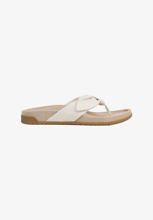 Beige flat sandal with cushioned footbed, brown rubber sole, and wide strap twisted into a knot over the toe post.