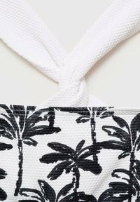 Černobílá látka s texturovaným povrchem, která zobrazuje vzor palmových listů; bílé tkané popruhy uvázané nahoře.