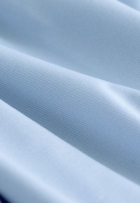 Tela azul claro con una textura de punto fina, mostrada en pliegues suaves y detalle en primer plano.