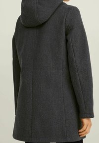 Cappotto di lana grigio scuro con cappuccio, caratterizzato da un taglio dritto, maniche lunghe e una texture sottile. Nessuna chiusura o decorazione visibile.