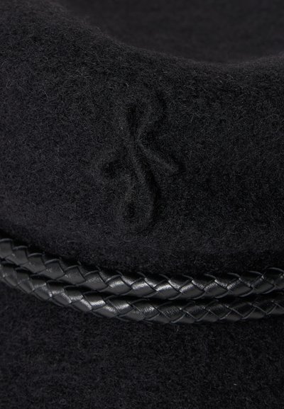 Gros plan d'un chapeau en laine noire avec des initiales en relief et une bande en cuir noir tressée autour de la base.