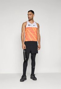 Muška sportska odjeća koja se sastoji od narančasto-bijele majice bez rukava s teksturiranim uzorkom, crnih kratkih hlača, crnih tajica i boce za vodu.