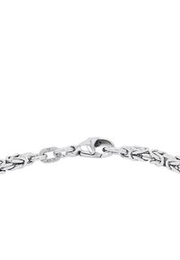 Silverfärgad kedjebracelet med sammanlänkade länkar, med en hummerklämma som stängning. Ytan är polerad och visar en reflekterande textur.