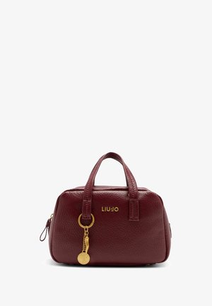 Bordeaux-lederne Handtasche mit runder Form, doppelten Oberhandgriffen, goldenen Logo-Details und einem dekorativen Schlüsselanhänger-Akzent. Strukturierte Oberfläche.