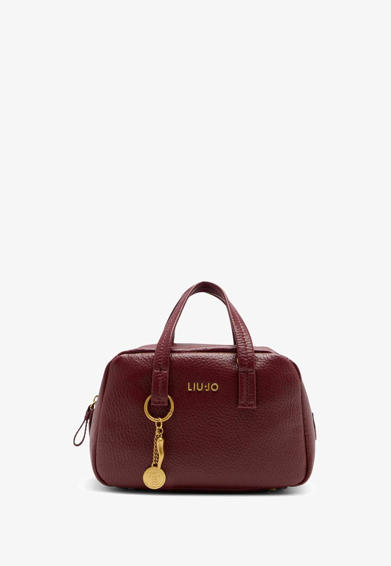 Bordowa skórzana torebka o zaokrąglonym kształcie, z podwójnymi uchwytami na górze, złotym detalem z logo oraz ozdobnym breloczkiem. Teksturowana powierzchnia.