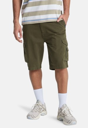 Olive green cargo shorts with multiple side pockets, cotton fabric, straight cut, and a hem slightly above the knee, paired with white socks and sneakers.