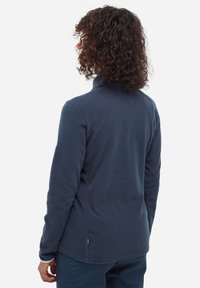 Marineblaue Fleecejacke mit hohem Kragen, strukturiertem Stoff und langen Ärmeln. Verfügt über Seitenpaneele und ein kleines Logo am Ärmel.