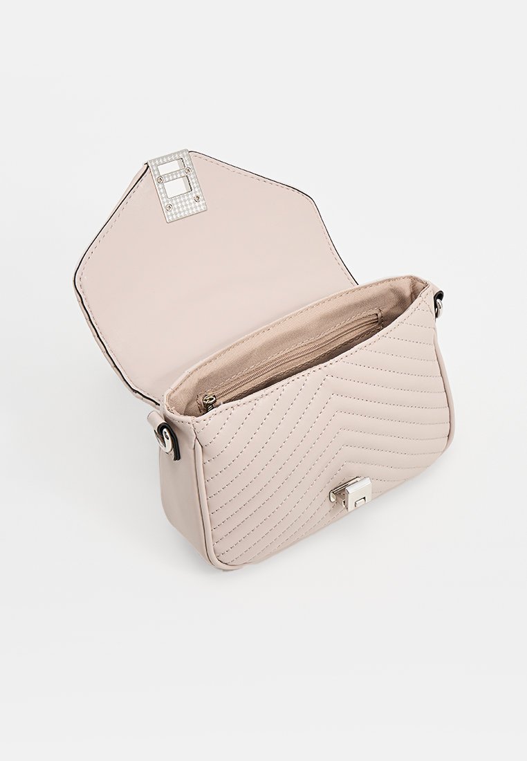 Kleine beige gesteppte Handtasche mit offener Klappe, die das Innenfach mit Reißverschluss sowie den silberfarbenen Verschluss und die dekorative Schnalle zeigt.
