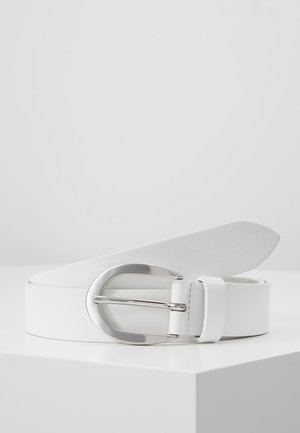 Ceinture en cuir blanc avec une grande boucle ovale argentée polie, enroulée et posée sur une surface blanche sur un fond gris clair.