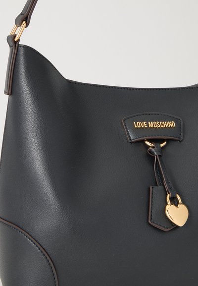 Черна кожена чанта с висулка във формата на златно сърце и лого "Love Moschino" отпред, прикрепена към един презрамка за рамо със златиста метална апликация.
