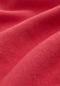 Tessuto rosso con una superficie morbida e testurizzata, caratterizzato da un sottile motivo a maglia che crea dolci pieghe e ondulazioni.