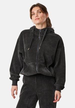 Black corduroy zip-up hoodie with a relaxed fit, ribbed texture, drawstring hood, and front pockets, paired with matching pants.
