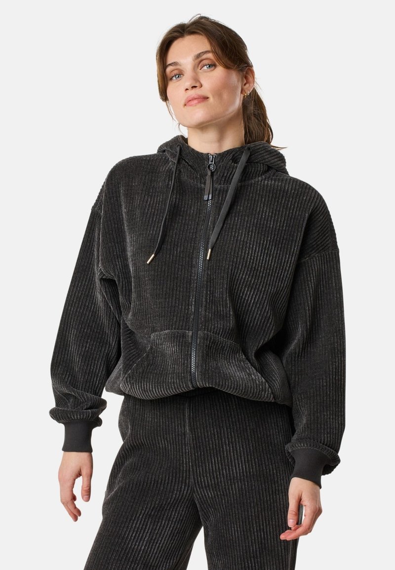Schwarze Cord-Collegejacke mit entspannter Passform, gerippter Textur, Kordelzugkapuze und vorderen Taschen, kombiniert mit passenden Hosen.