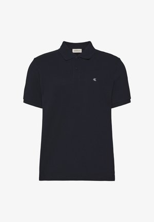 Črna polo majica s kratkimi rokavi, dvema gumboma in majhnim belim logotipom "cK" na levi strani prsnega koša.