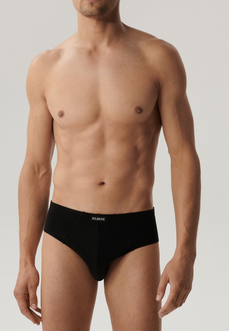 Czarne męskie majtki typu slip wykonane z bawełny z paskiem z logo. Ich design charakteryzuje się średnim stanem, gładką teksturą i brakiem widocznych szwów.