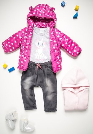 Veste rembourrée rose avec des motifs en cœur, t-shirt graphique gris, pantalon gris foncé, hoodie en tricot rose et bottines argentées brillantes disposés sur un fond blanc.