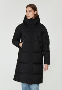 Abrigo de plumas negro con un cuello alto, bolsillos con cremallera y una silueta recta. Presenta una textura acolchada y un diseño de longitud media.