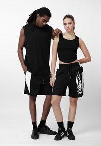 Top e calções atléticos pretos para ambos, com detalhes brancos contrastantes. Mangas curtas, textura canelada e design gráfico nos calções.