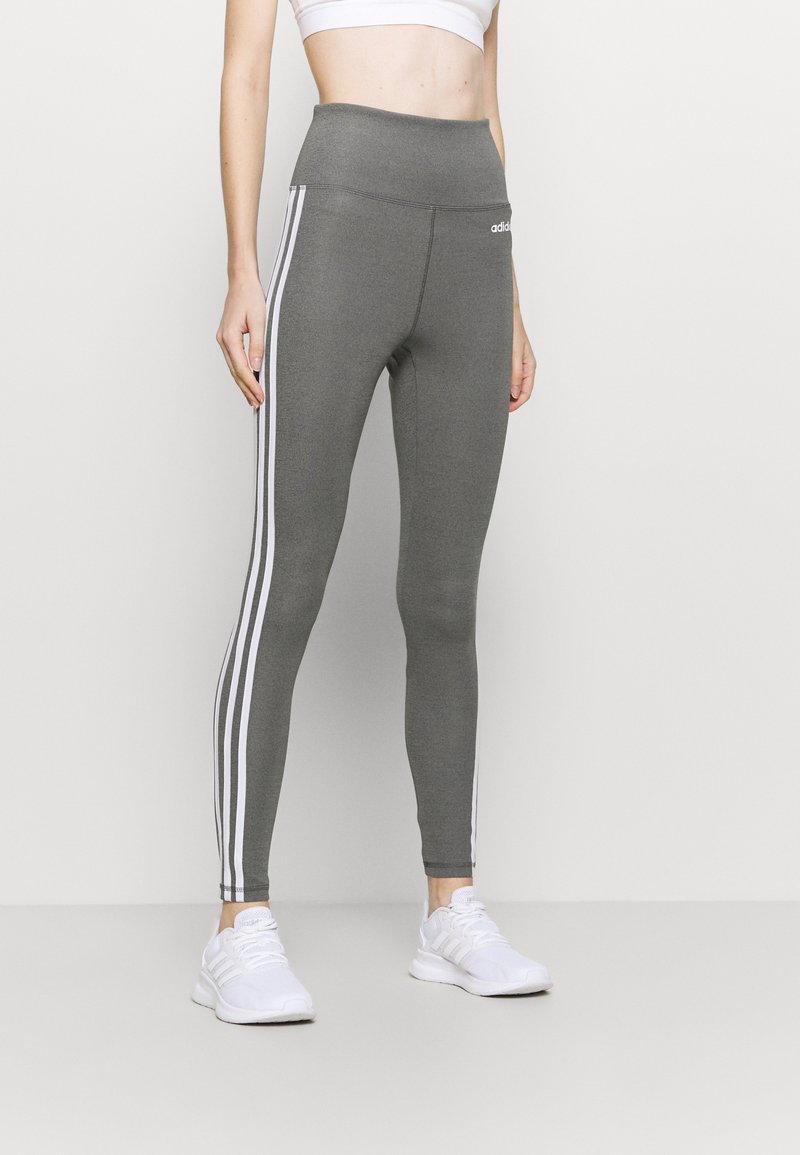 Leggings grigi con vita alta. Presentano un design a tre strisce bianche lungo i lati. Realizzati in un tessuto elastico per il massimo comfort.