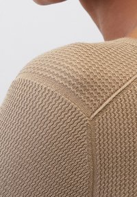 Gebreide pullover in beige met een structuurpatroon, voorzien van een ronde halslijn en een naaddetail op de schouder.