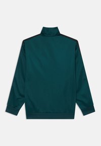 Blazer desportivo azul esmeralda com gola alta, punhos canelados e detalhes em preto nos ombros. Tecido suave e leve com um corte descontraído.
