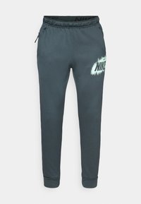 Ciemnoszare dresy wykonane z miękkiego materiału, z elastycznym paskiem w talii, bocznymi kieszeniami oraz dużym białym logo Nike z efektem sprayu.