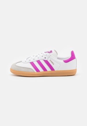 Hvid Adidas Samba sneaker med lyserøde striber, gummisål og ruskindståkappe, vist i profil på hvid baggrund.