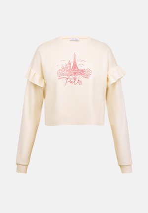 Korte crème trui met ruches op de mouwen, voorzien van een roze graphic van de Eiffeltoren en het woord "Parijs."