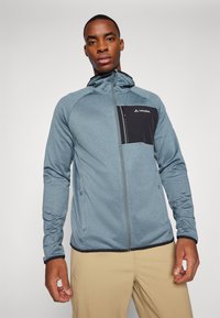 Giacca con cappuccio da uomo blu, con una tasca sul petto nera con zip, zip grigie e polsini regolabili. Tessuto morbido con un design aderente.