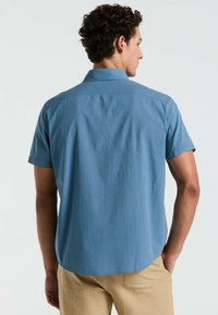 Korte mouwen, geknoopte blouse in lichtblauwe stof met een gestructureerde afwerking, met een rechte zoom en een relaxed fit. Achteraanzicht getoond.