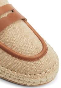 Scarpe beige intrecciate con tomaia in tessuto testurizzato e dettagli in pelle marrone, caratterizzate da un bordo cucito e un elemento decorativo a taglio.