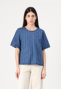 Top in denim blu con strisce verticali bianche, maniche corte, scollo rotondo, orlo grezzo, tessuto testurizzato e vestibilità casual.