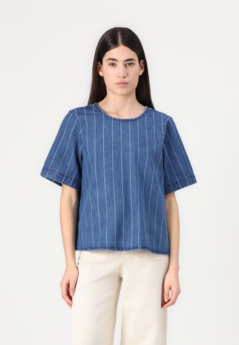 Top in denim blu con strisce verticali bianche, maniche corte, scollo rotondo, orlo grezzo, tessuto testurizzato e vestibilità casual.