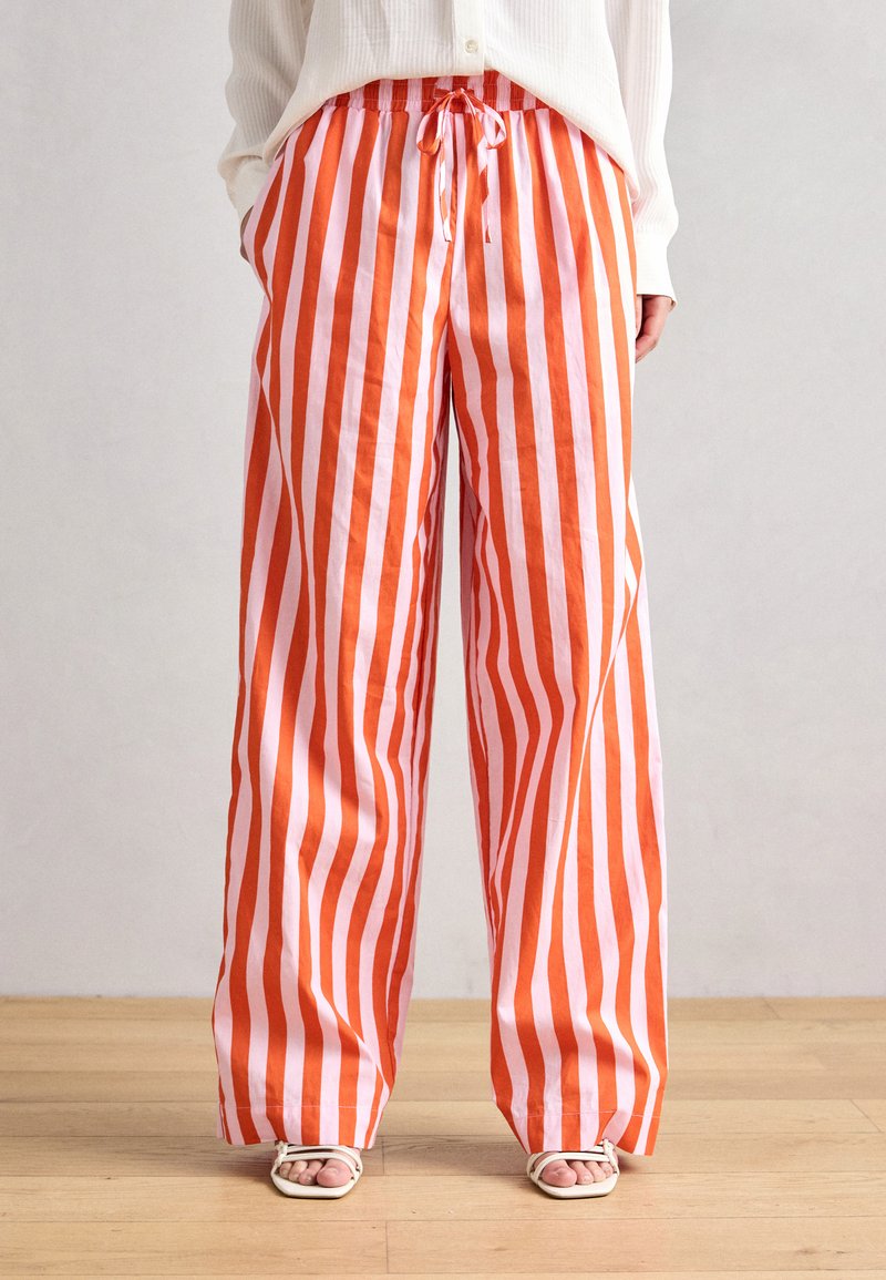 Orange and white striped wide-leg pants with drawstring waist, made from lightweight fabric, featuring a relaxed fit and smooth texture.