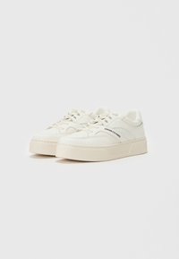 Weiße Ledersneaker mit strukturierten, off-white Plattformsohlen. Zu den Merkmalen gehören Perforationen, Schnürsenkel und das "Armani Exchange"-Logo an der Seite.