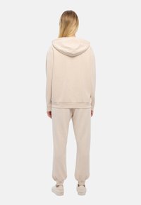 Completo di felpa con cappuccio e pantaloni della tuta beige, realizzato in morbido tessuto, con cappuccio regolabile, polsini a coste e design a gamba affusolata.