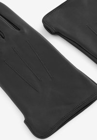 Guanti in pelle nera con una texture liscia, tre linee di cucitura verticali sul dorso e un design aperto per una maggiore destrezza delle dita.
