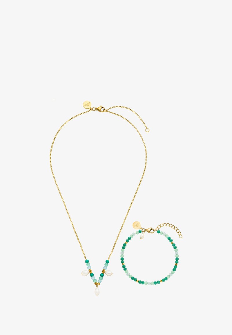 Goldene Halskette und Armband mit grünen und blauen Perlen sowie Perlenakzenten. Die Halskette hat eine V-Form; das Armband ist kreisförmig.