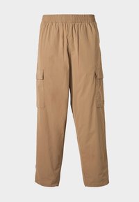 Pantalons cargo beiges avec une taille élastique, dotés de plusieurs poches latérales et d'une texture légère et lisse. Design à jambe droite.