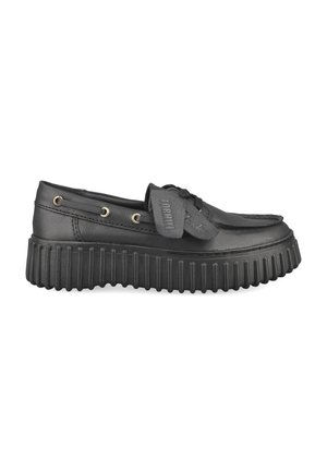 Mocassin en cuir noir avec semelle épaisse rainurée, laçage à l'avant et œillets métalliques sur les côtés.