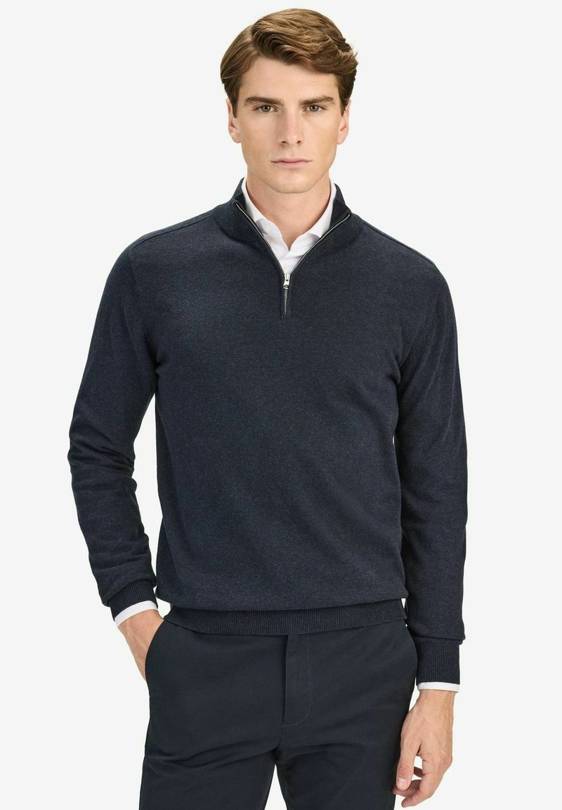 Merenmonttinen neulepuvussa on puolivetoketjullinen kaulus, pehmeä rakenne ja vartalonmyötäiset hihat. Muotoiltu valkoisen paidan päälle kontrastiksi. Rentoa, sovitettua muotoilua.