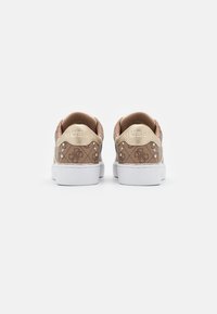 Baskets brunes à motif avec une semelle blanche. Présentent des accents dorés et des détails texturés sur le talon avec "GUESS" embossé. Doublure en tissu douce.